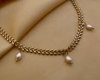 Gold necklace with intricate woven links and three champagne pearl charms hanging from the center
