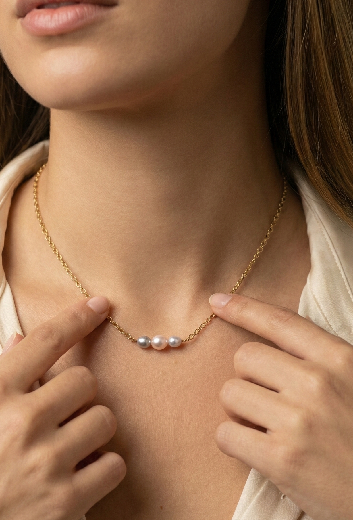 Delicate gold link chain necklace featuring a trio of pearls: a central oval champagne pearl flanked by two smaller, irregular grey baroque pearls