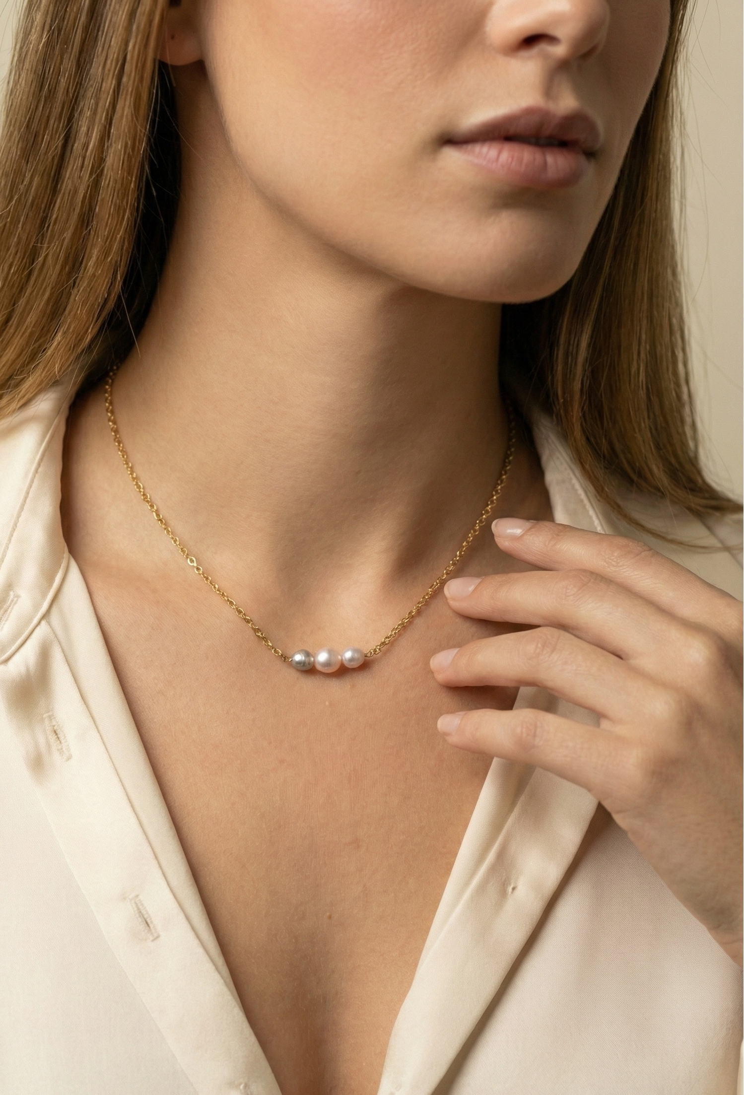 Delicate gold link chain necklace featuring a trio of pearls: a central oval champagne pearl flanked by two smaller, irregular grey baroque pearls
