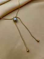 Gold necklace with a pendant on a beige fabric background