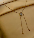 Gold necklace with a pendant on a beige fabric background