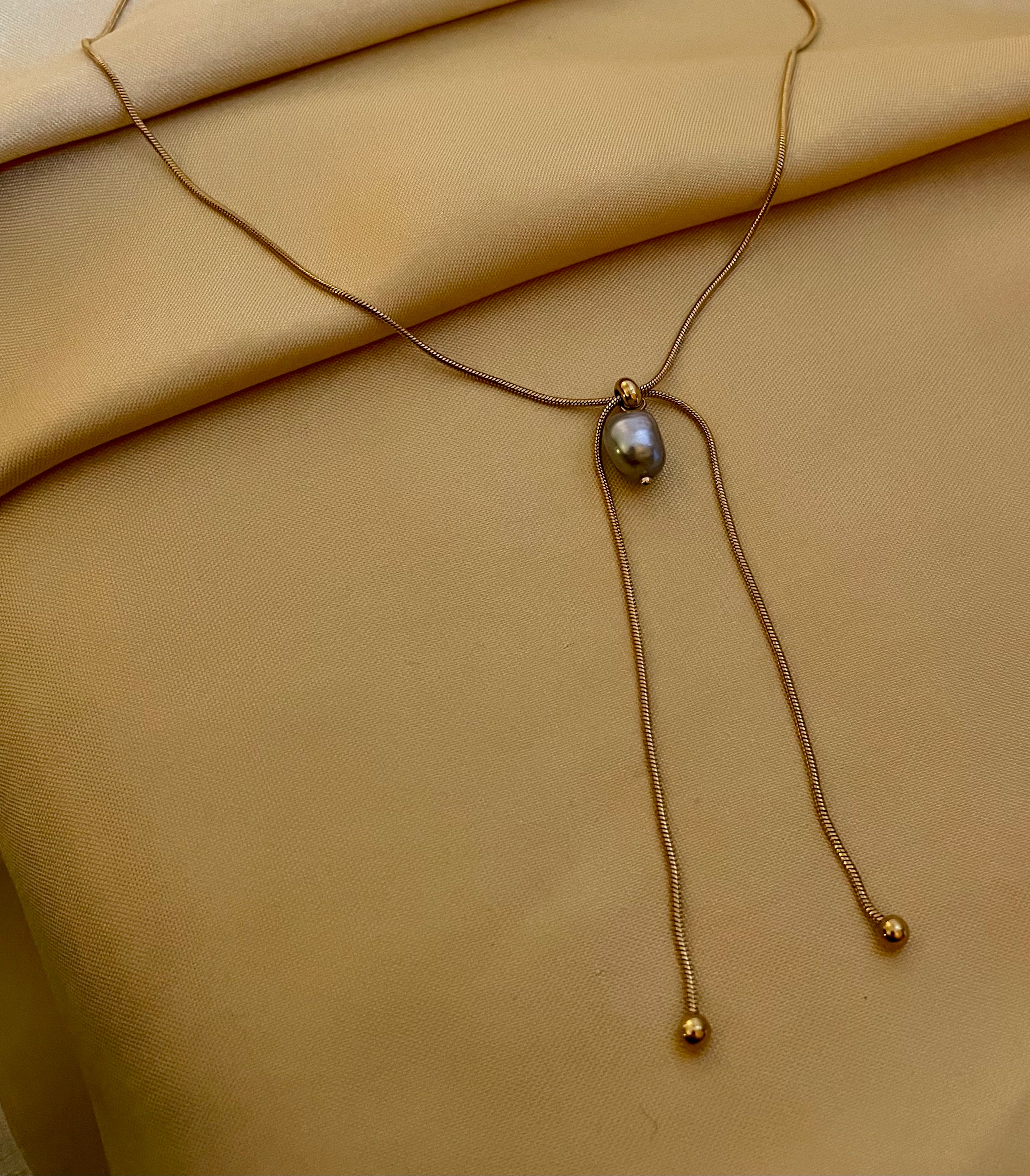 Gold necklace with a pendant on a beige fabric background