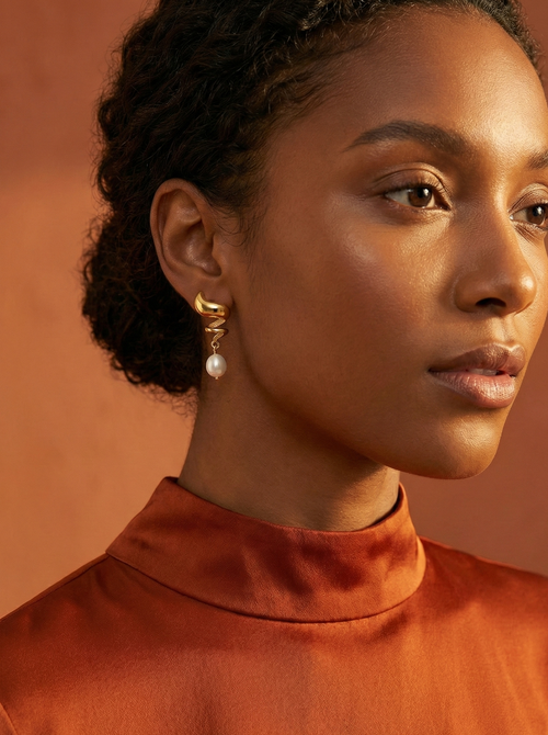 Close-up detail of the light-reflecting hammered gold texture on Alizee earrings paired with a high-lustre AAA freshwater pearl