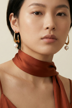 Woman wearing gold earrings with pearls against a neutral background