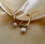 Gold hoop earrings with pearls on a beige satin background