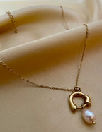 dainty gold chain necklace with a sculptural molten gold charm and a single freshwater pearl drop in soft pink