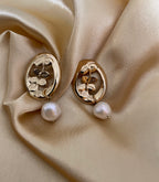 18k Gold earrings with vintage french stype floral leaf designs and baroque white pearls on beige fabric