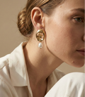 Close-up of a model wearing vintage stype french 18k gold earrings with a cultured baroque pearl
