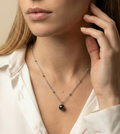 Model wearing single black round pearl pendant on dainty silver beaded chain necklace