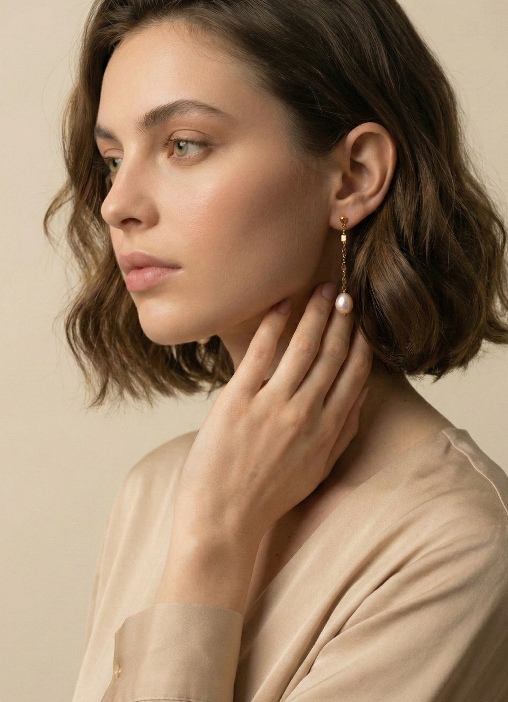 femme portant des boucles d'oreilles pendantes en perles baroques roses sur une chaîne en or, style parisien