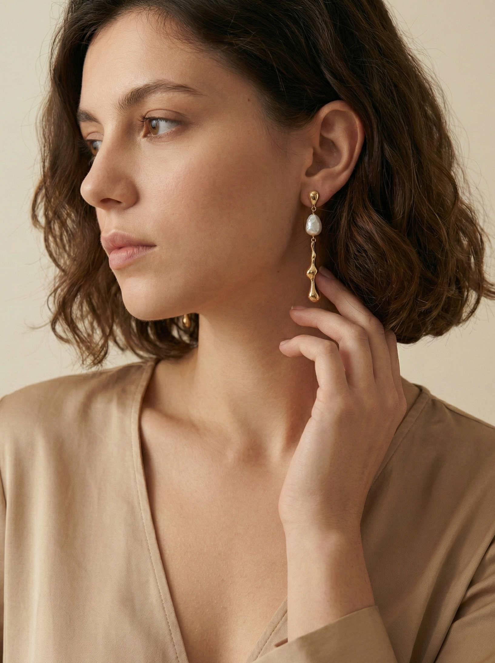 Détail d'une boucle d'oreille élégante en or et perle portée par une femme, style minimaliste et chic parisien