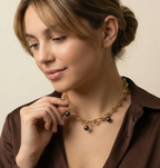 Model wearing a chunky gold link necklace with black pearl pendants, highlighting the luster and gold detailing