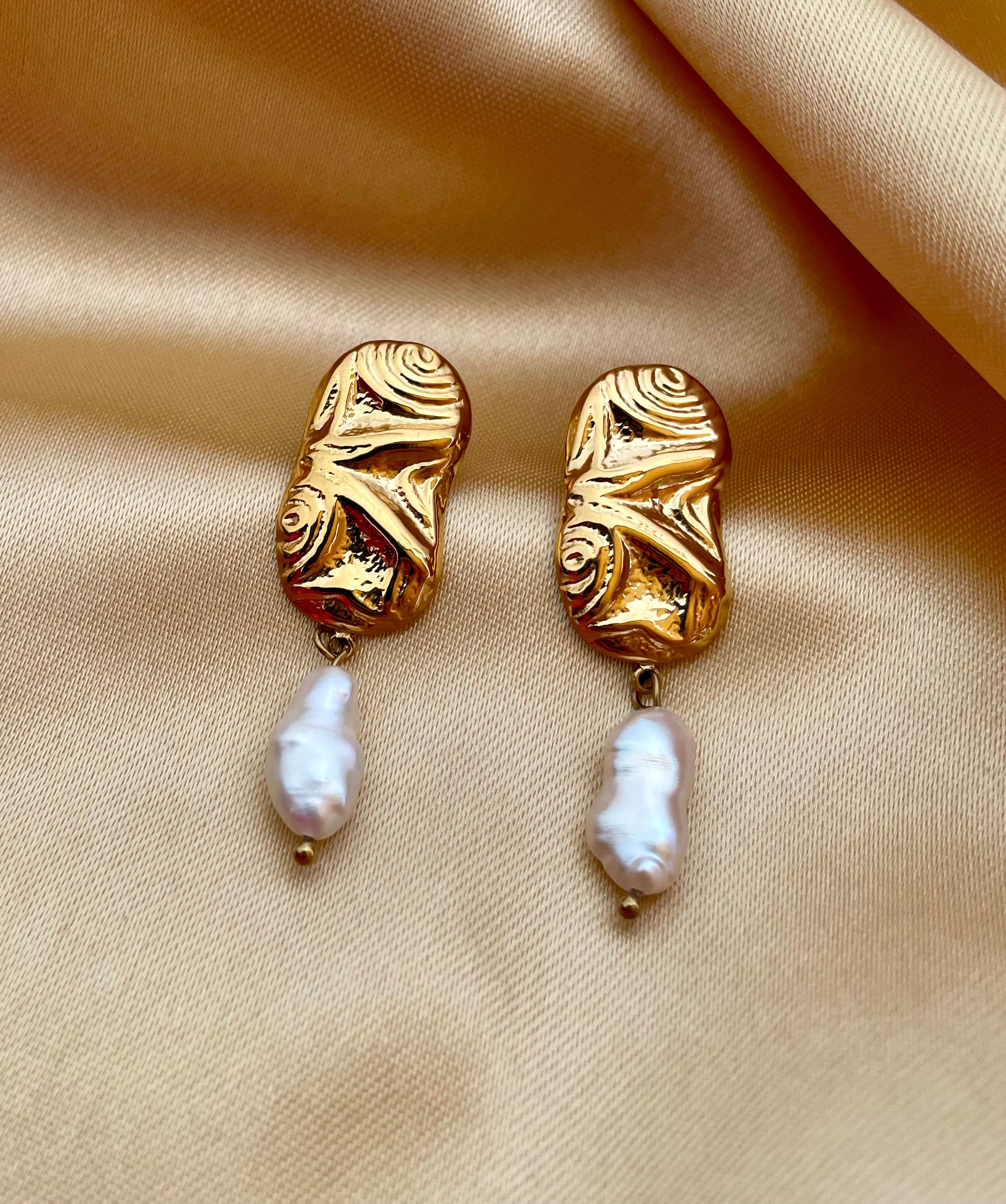 Close-up of a sculptured aztec organic 18k gold earrings with japanese keshi pearls