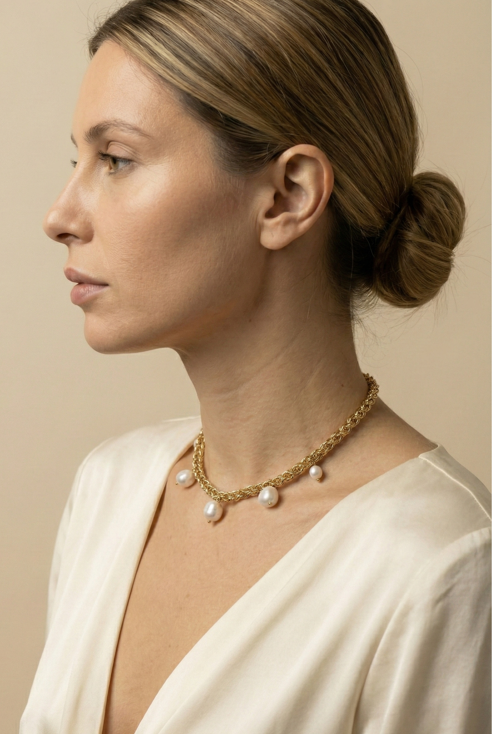 Elegant gold choker necklace featuring organic baroque pearls, shown on a model with an updo hairstyle and silk blouse