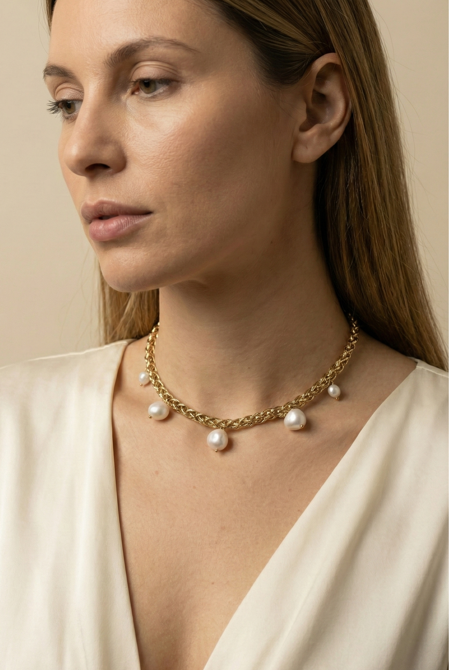 Elegant gold choker necklace featuring organic baroque pearls, shown on a model with an updo hairstyle and silk blouse