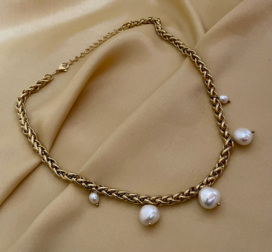 Elegant gold choker necklace featuring organic baroque pearls, shown on a model with an updo hairstyle and silk blouse