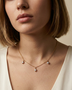 Close-up of a woman wearing a delicate necklace with small pearl pendants on a neutral background