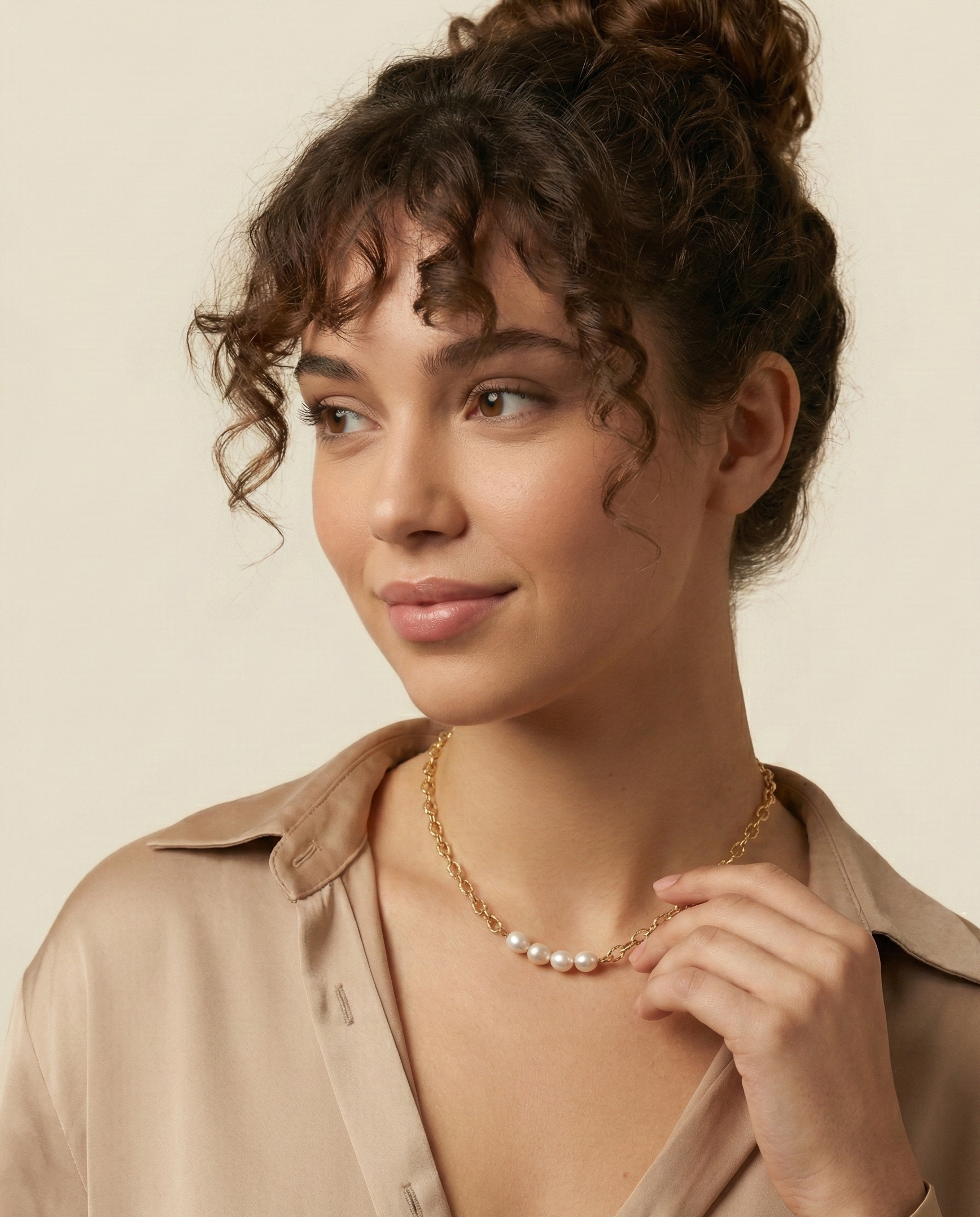 Close-up of gold link necklace featuring four high-luster oval white pearls worn on a model