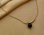 Elegant gold curved bar necklace with black pearl pendant worn by a model. Minimalist jewelry design featuring a high-luster round black pearl and sleek gold spacer on a delicate chain