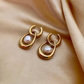 Close-up editorial photography of a gold hoop drop earring featuring a suspended white high-luster pearl