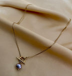 gold double-strand lariat necklace featuring a lustrous grey baroque pearl and toggle clasp