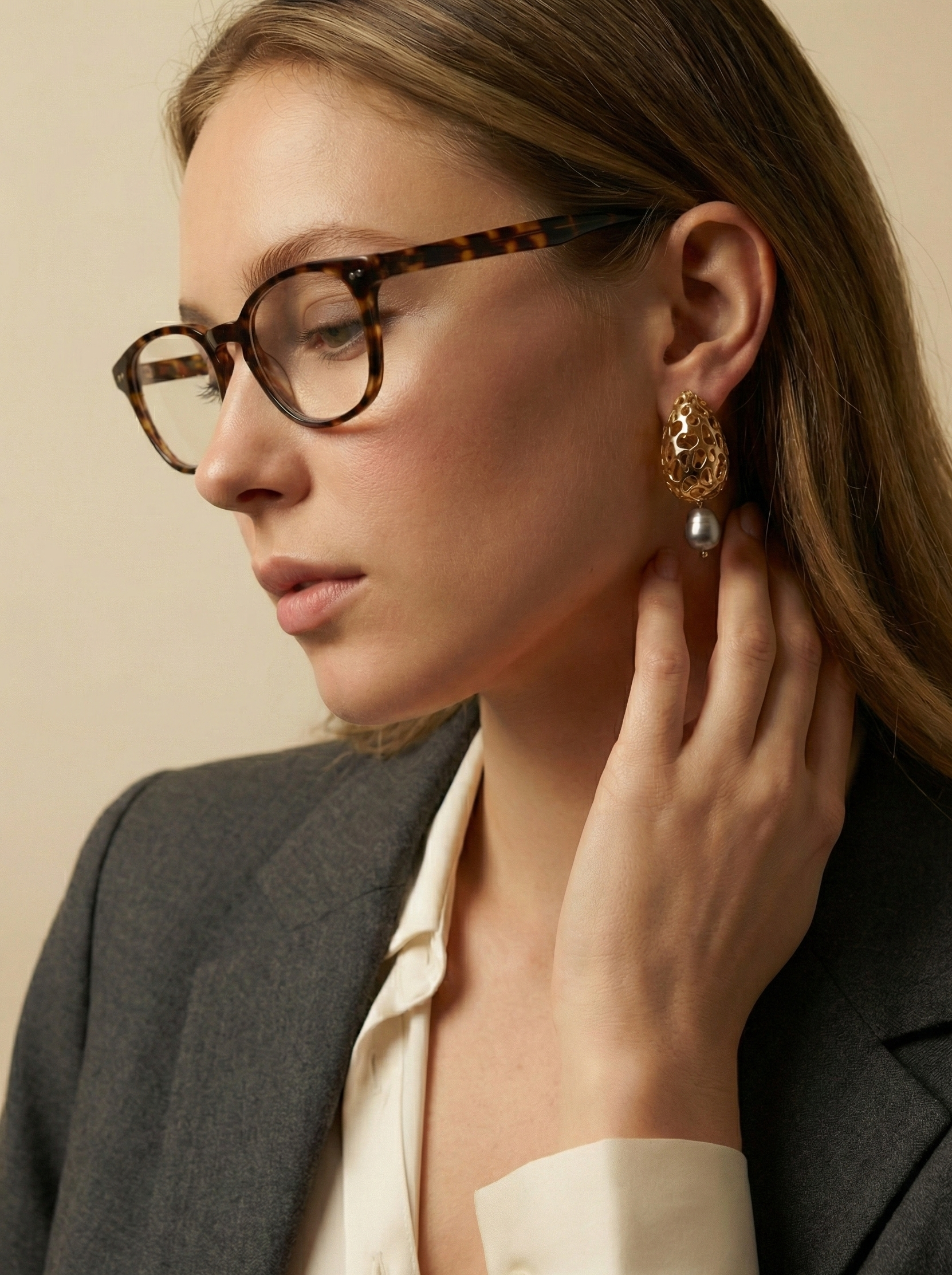 Close-up detail of luxury gold lattice teardrop earrings featuring a suspended metallic grey freshwater baroque pearl with high chrome luster
