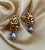 Close-up detail of luxury gold lattice teardrop earrings featuring a suspended metallic grey pearl with high chrome luster
