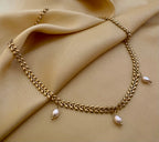 Close-up of a gold leaf-pattern chain necklace featuring three dangling champagne white pearls