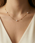 Minimalist gold jewelry styling featuring a delicate necklace with three freshwater pearls on a young female model with soft, warm lighting