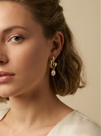 Editorial close-up of a model in a Parisian chic style wearing an ivory silk shirt. She is wearing unique, organic-shaped gold earrings featuring lustrous pink oval pearl drops