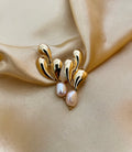 Editorial close-up of a unique, organic-shaped gold earrings featuring lustrous pink oval pearl drops