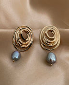 Close-up of a gold concentric spiral statement earrings with a lustrous organic freshwater grey pearl drop