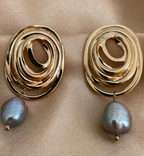 Close-up of a gold concentric spiral statement earrings with a lustrous organic freshwater grey pearl drop