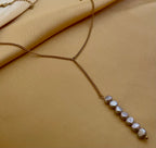 Gold lariat necklace with organic grey baroque pearls worn by a model in ivory silk