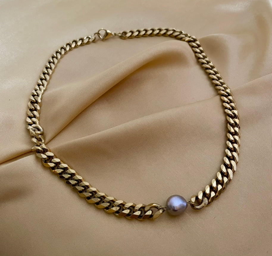 Close-up of a gold Cuban link chain necklace featuring a single, centered AAA grade grey baroque pearl
