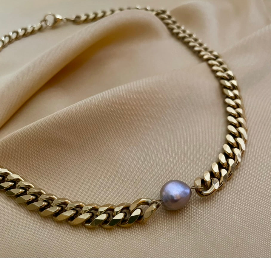 Close-up of a gold Cuban link chain necklace featuring a single, centered AAA grade grey baroque pearl