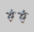 Macro detail showing the intricate textures of handcrafted silver flower earrings and the iridescence of the freshwater pearl attached