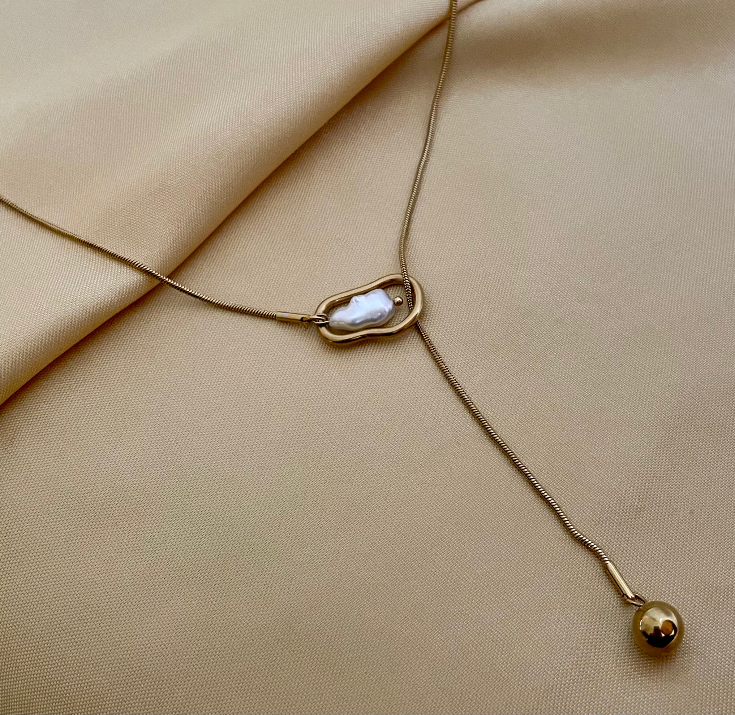 Gold necklace with a pendant on a beige fabric background