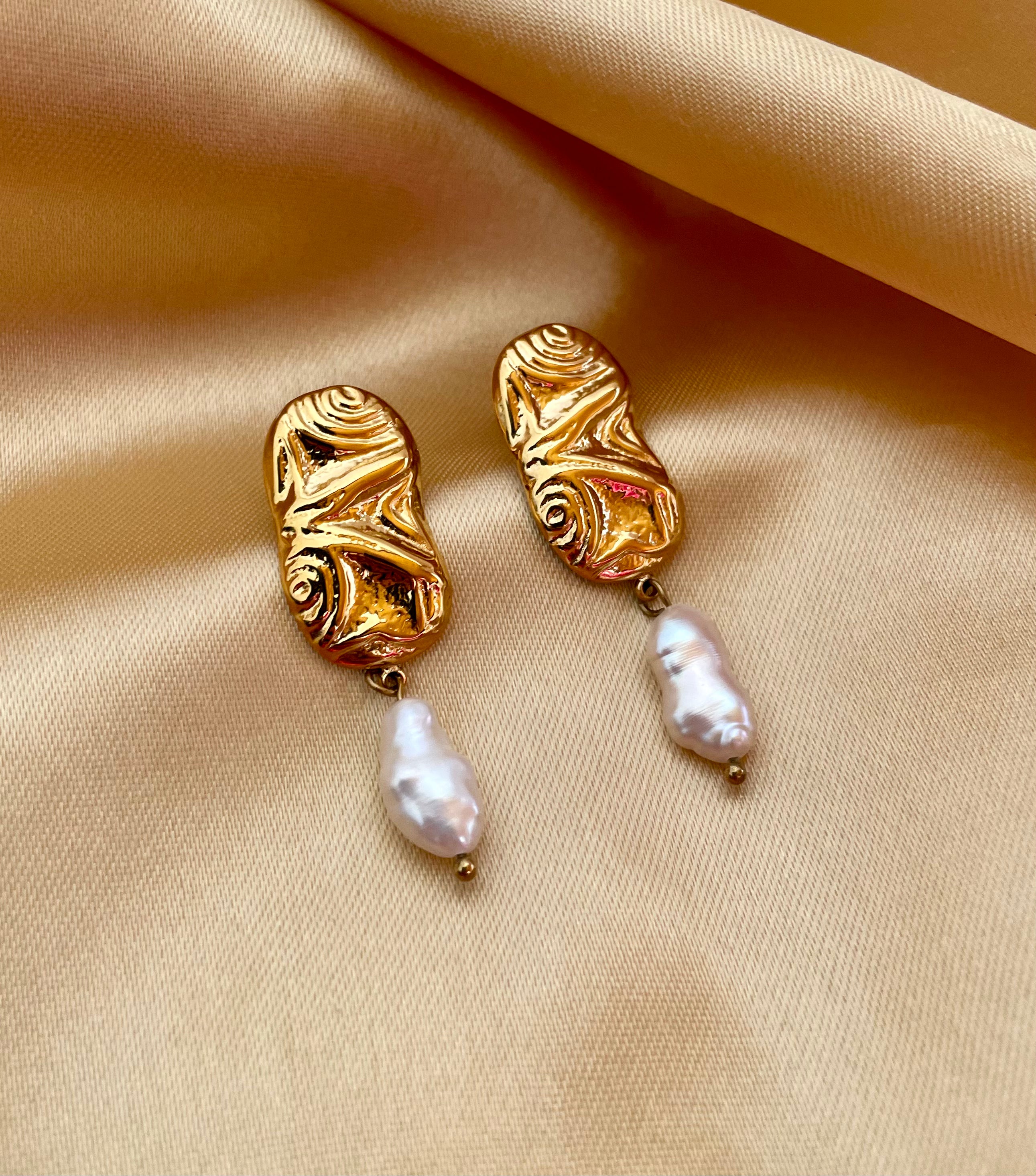 Close-up of a sculptured aztec organic 18k gold earrings with japanese keshi pearls