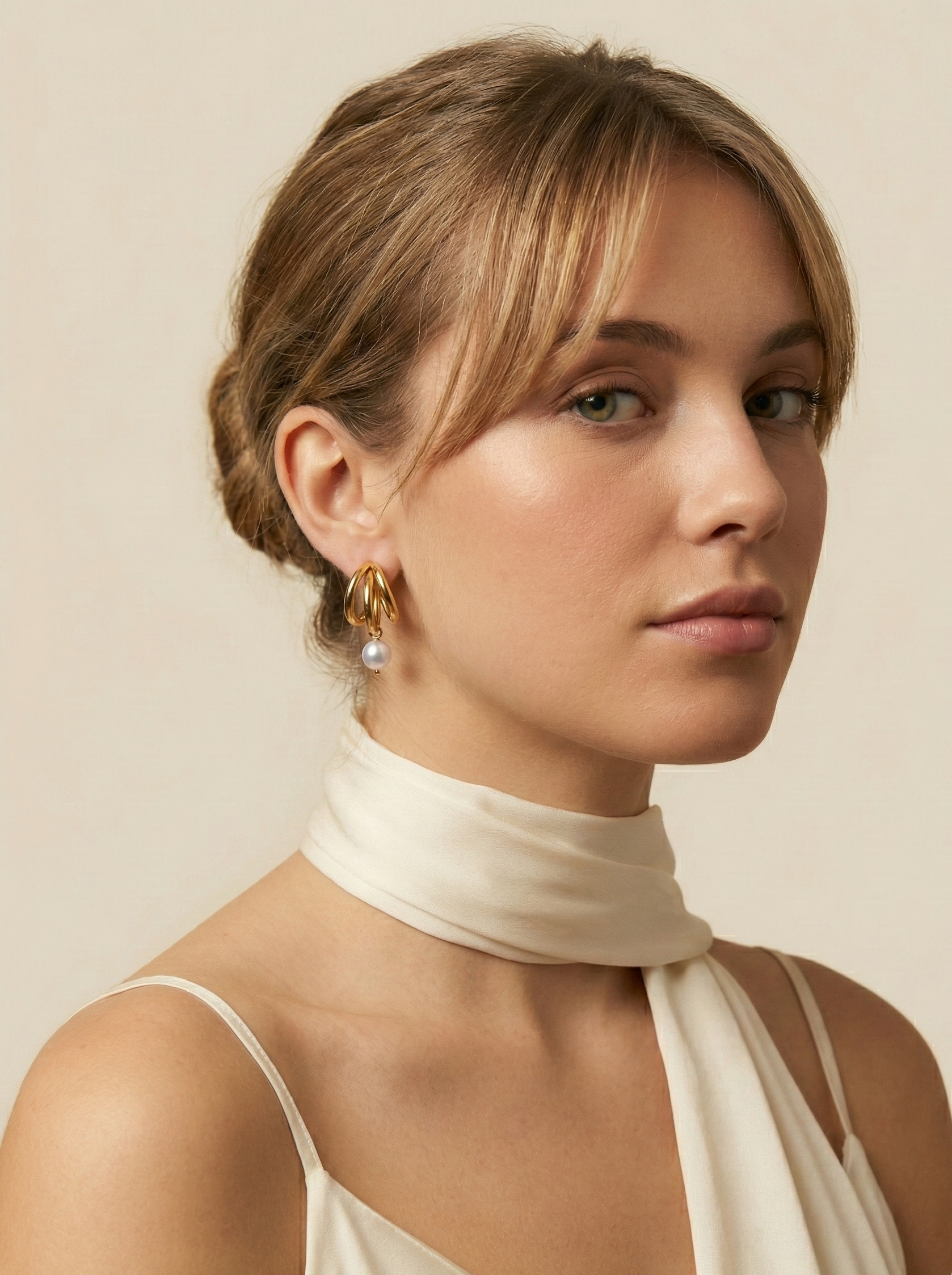 Model wearing chunky 18k gold split hoop earrings with white pearl dangles. Close-up side profile showing ear styling and jewelry scale