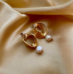 High-fashion jewelry photography featuring elegant gold and pearl earrings in soft studio lighting.