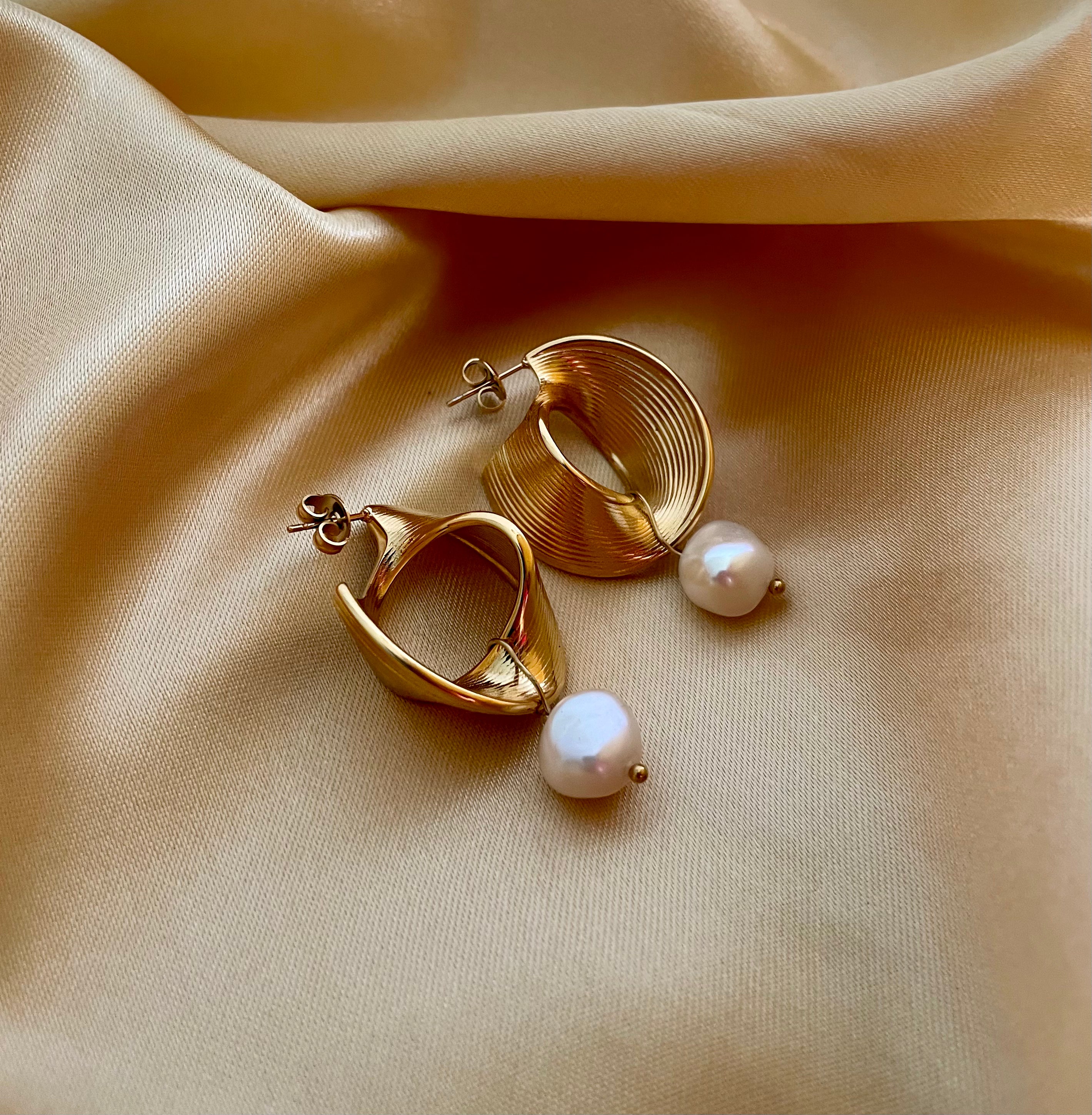 High-fashion jewelry photography featuring elegant gold and pearl earrings in soft studio lighting.