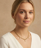 Model wearing a dainty gold wheat chain necklace with oval pearl pendants, styled with a white silk top for a minimalist bridal or evening look