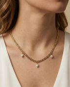 Model wearing a dainty gold wheat chain necklace with baroque pearl pendants, styled with a white silk top for a minimalist bridal or evening look