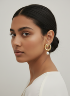 Woman wearing Miranda chunky gold croissant hoop earrings with white pearl drops. Stylish statement jewelry for everyday or evening wear.