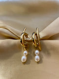 Modern gold pearl dangle earrings on ear; luxury bridal jewelry with high luster twin freshwater pearls and architectural gold design