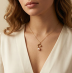Woman wearing a dainty gold chain necklace with a sculptural molten gold charm and a single baroque freshwater pearl drop in soft pink