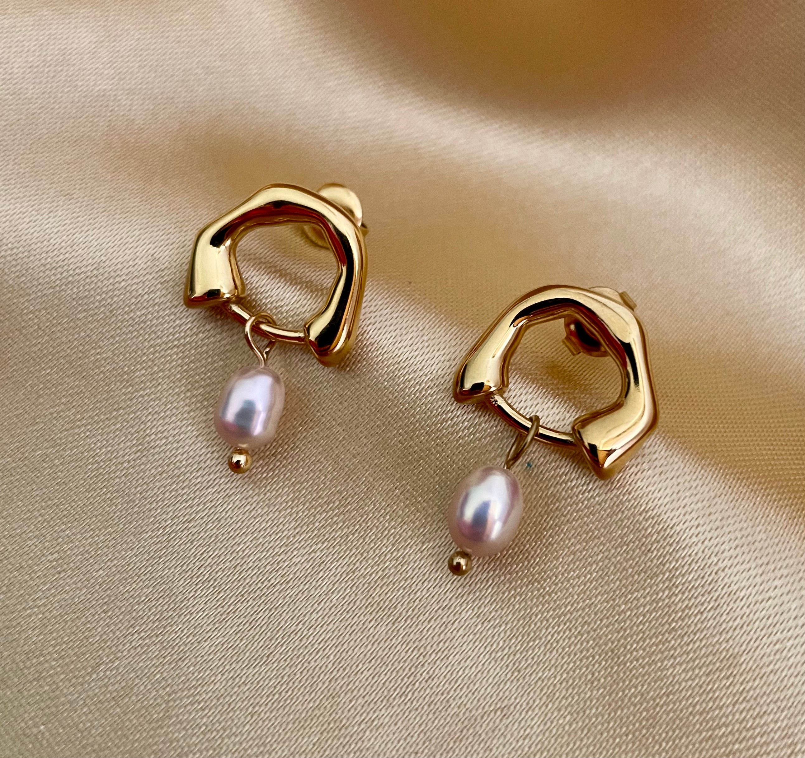 Close-up detail of organic gold huggie hoop earrings featuring a high-luster pink oval freshwater pearl drop