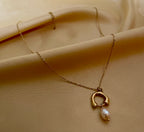 gold organic open-circle pendant necklace featuring a suspended lustrous champagne-pink oval pearl