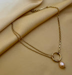Gold necklace with a pearl pendant on beige fabric